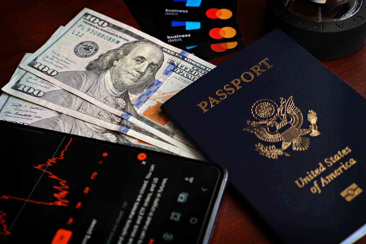 services-04 US passport with hundred-dollar bills, credit cards and smartphone showing stock data.