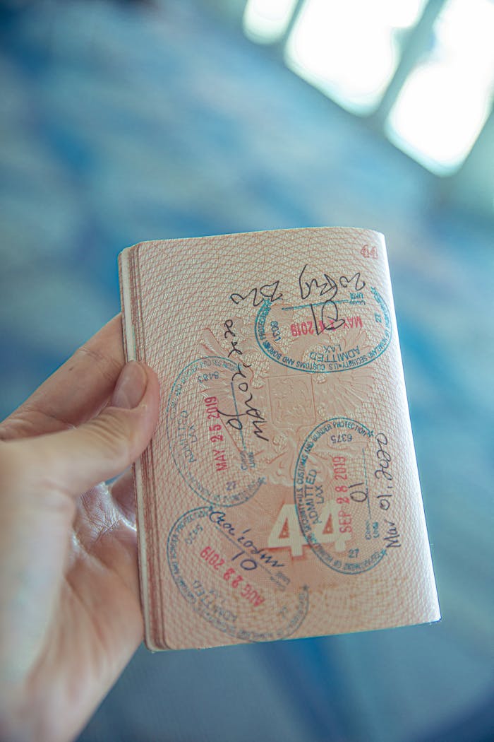services-01 A close-up view of a hand holding an open passport with various stamps, highlighting travel experiences.